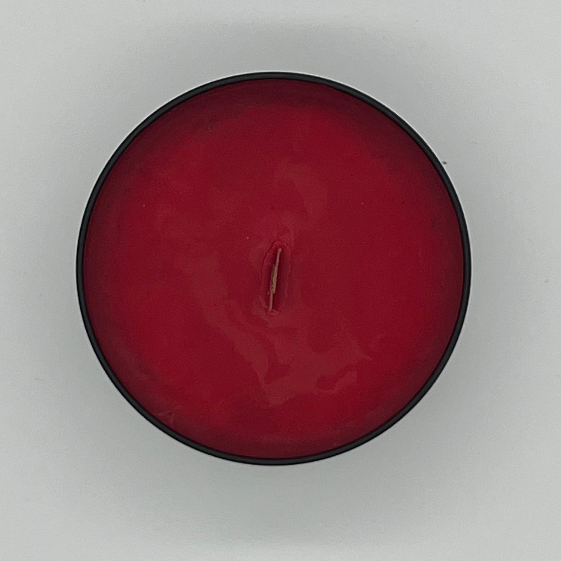 Red candle in a black holder on a white background.
